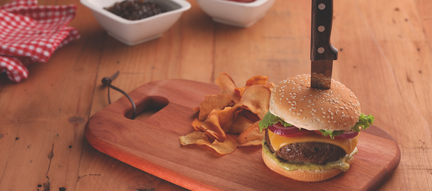 Beef burger with cheese and salad served on a wooden board